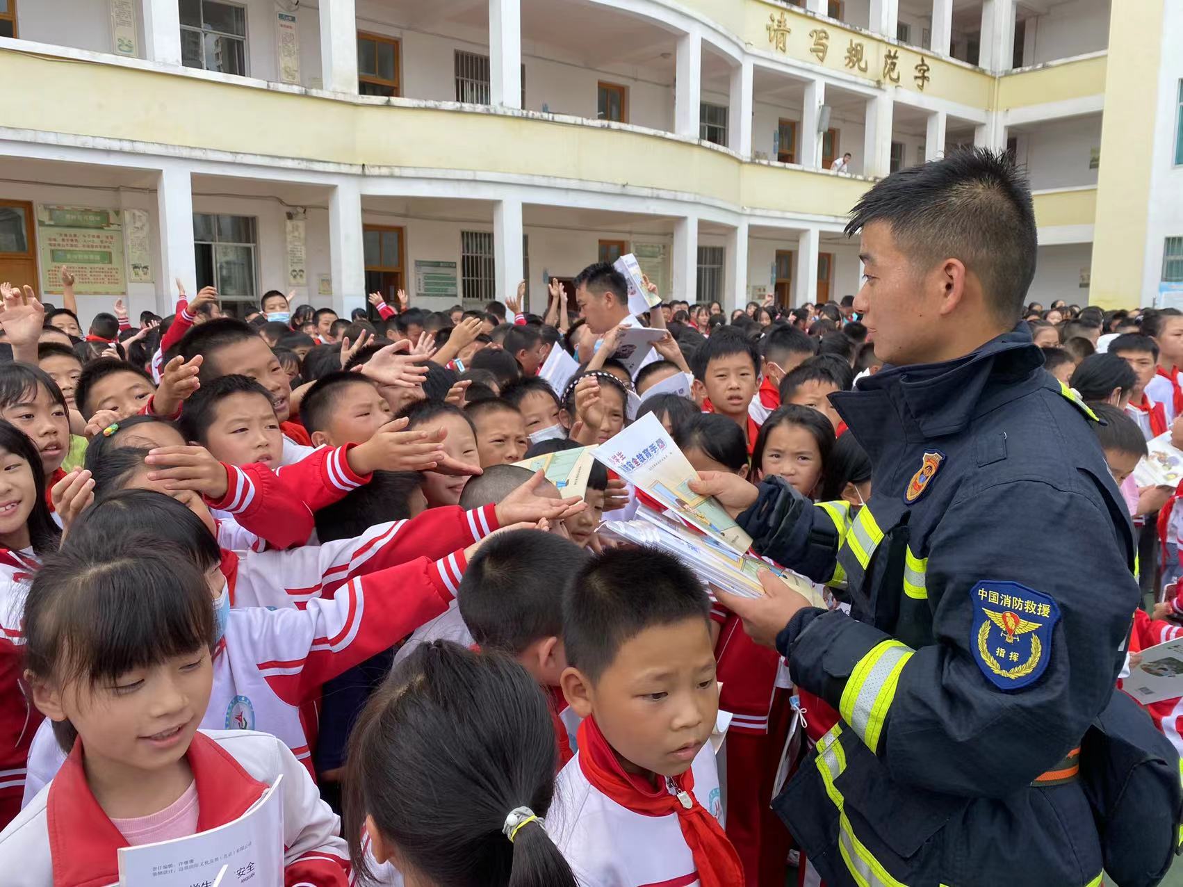 消防员给小朋友们发放中小学生消防安全知识读本.jpg